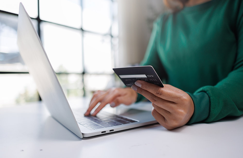CVV e CVC: cosa sono e a cosa servono i codici di sicurezza delle carte Persona che digita al computer portatile con una carta di credito in mano